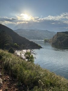 Sunset view over Horsetooth Reservoir from the Bay to Bay Trail in Fort Collins, with hills, water reflections, and soft cloud cover